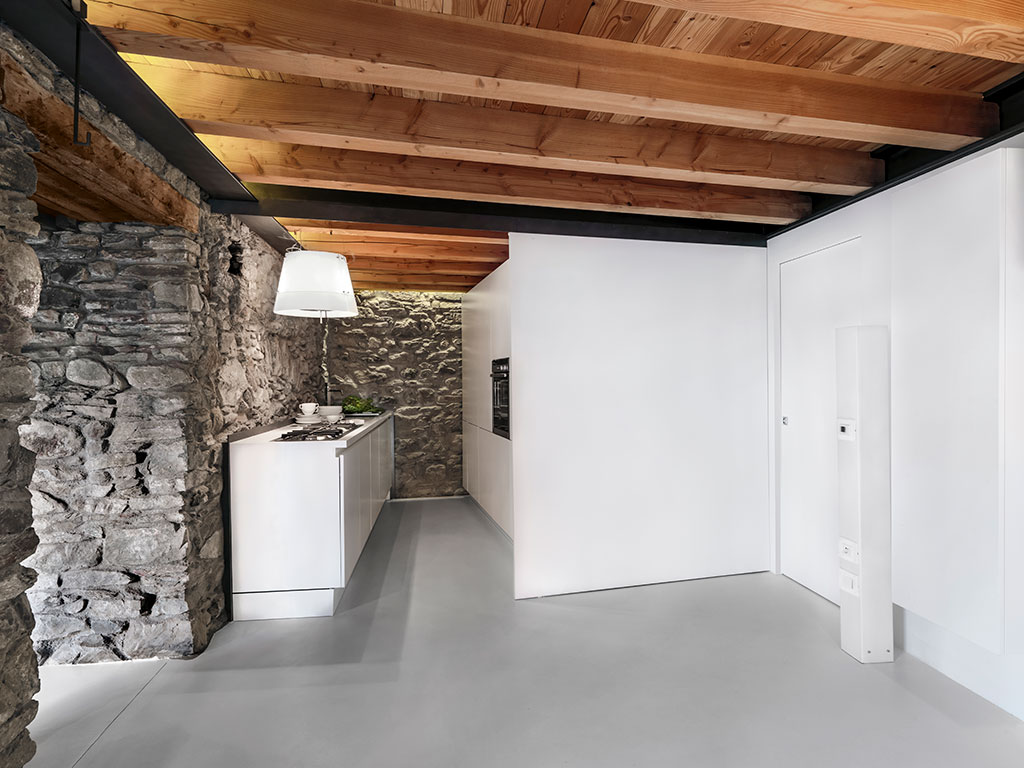 cocina moderna en una casa reformada con paredes de piedra vista y vigas de madera